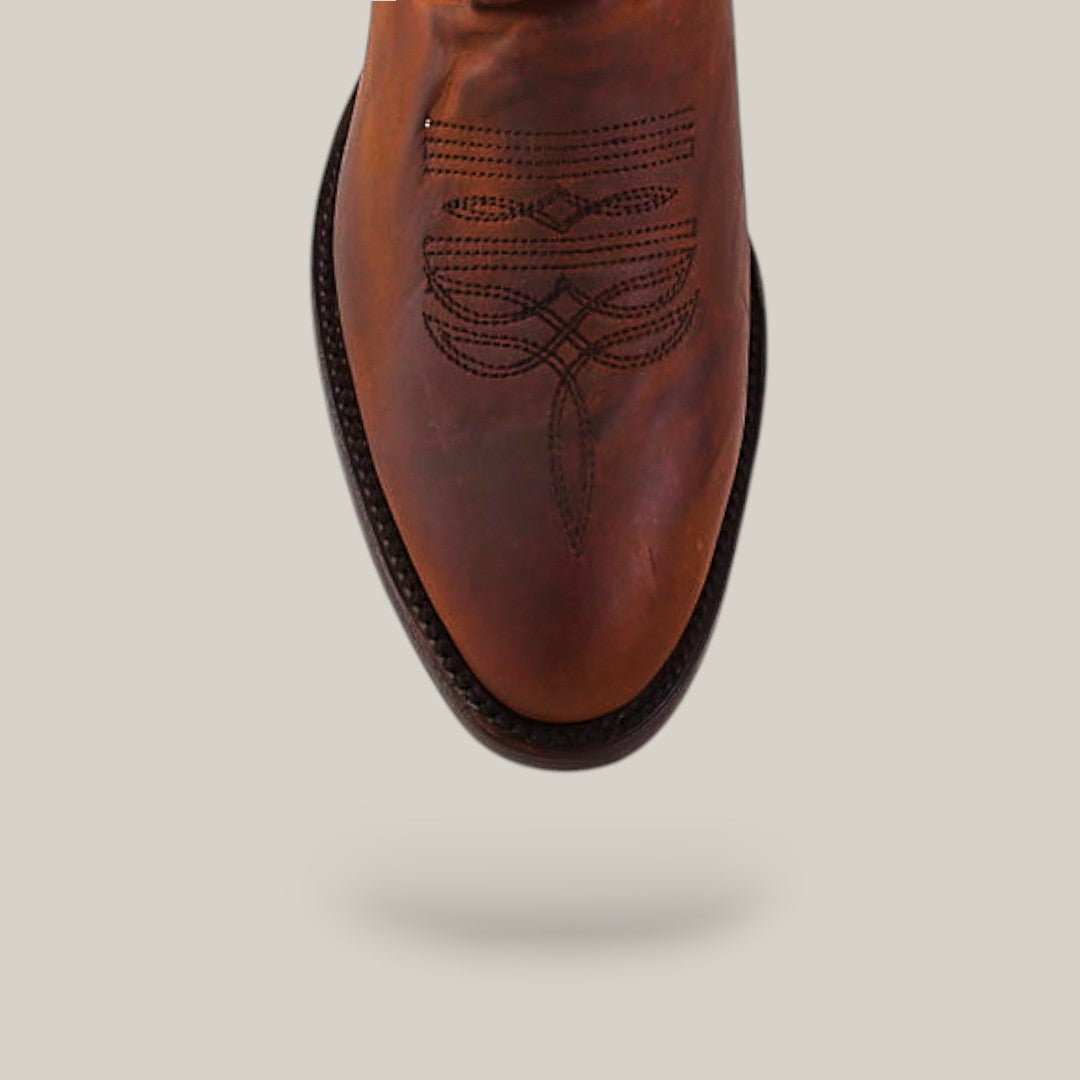 The Dutton - Brick - Roper Toe cowboy boot features brown leather, decorative toe stitching, and a dark brown welt, shown from above against a plain light background.
