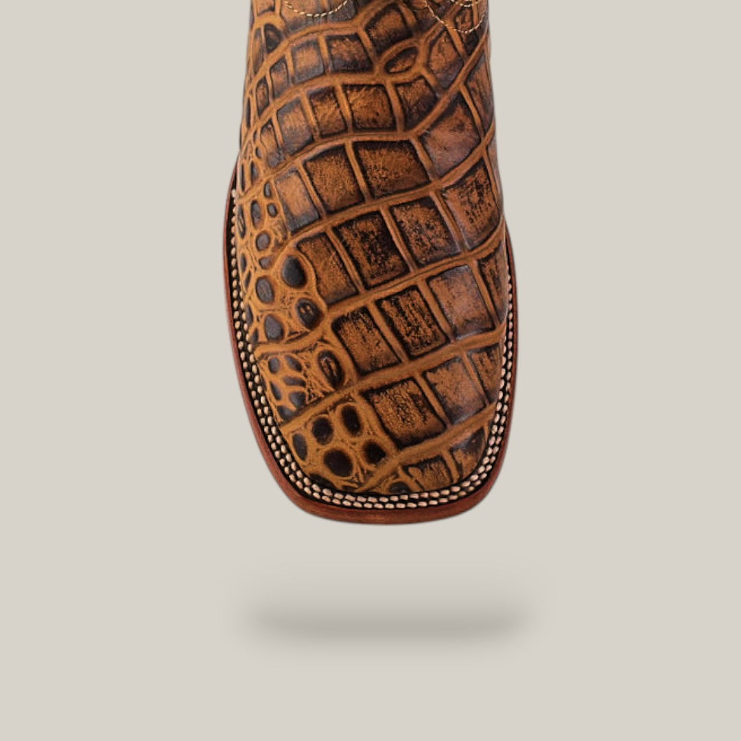 Top view of the Jonh - Orix - Square Toe boot in brown cowhide with a crocodile-like texture, premium leather, white edge stitching, and a square toe, displayed against a light beige background.
