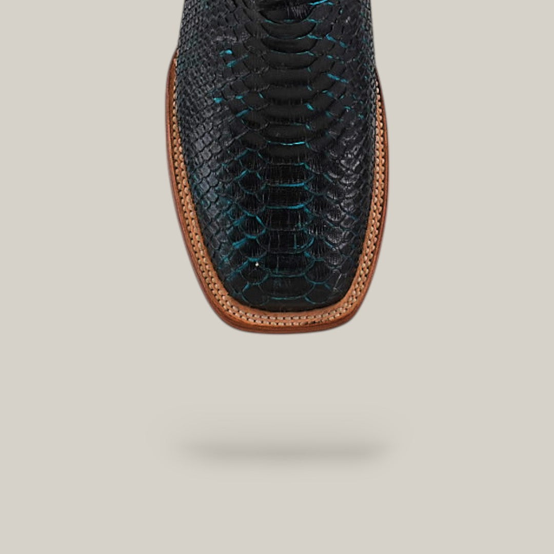 A close-up of the Exotic Python - Dark Blue - Square Toe cowboy boot, highlighting its square toe and brown leather welt, against a plain light beige background.