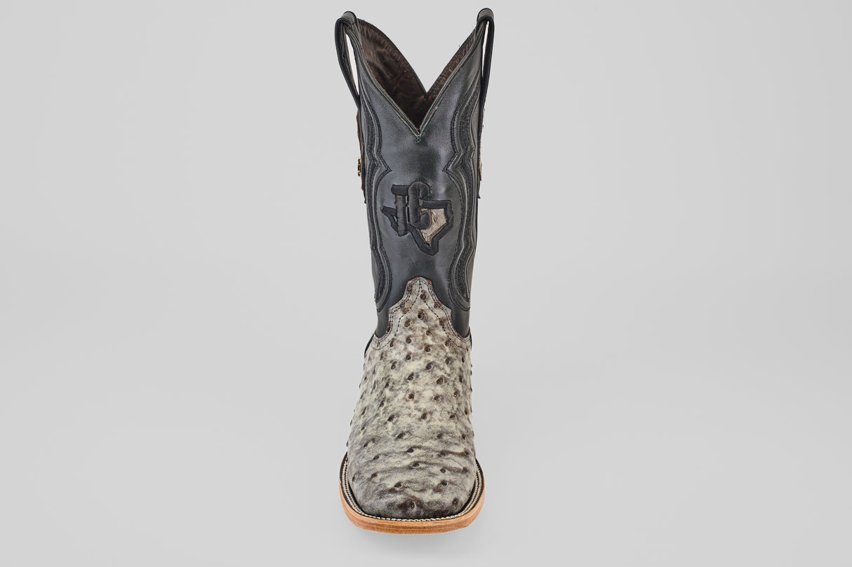 A single mens Exotic Full Quilt Ostrich - Nicotine - Square Toe boot with a textured light gray and black leather foot, black leather upper, decorative stitching, and Texas emblem, shown on a plain white background.
