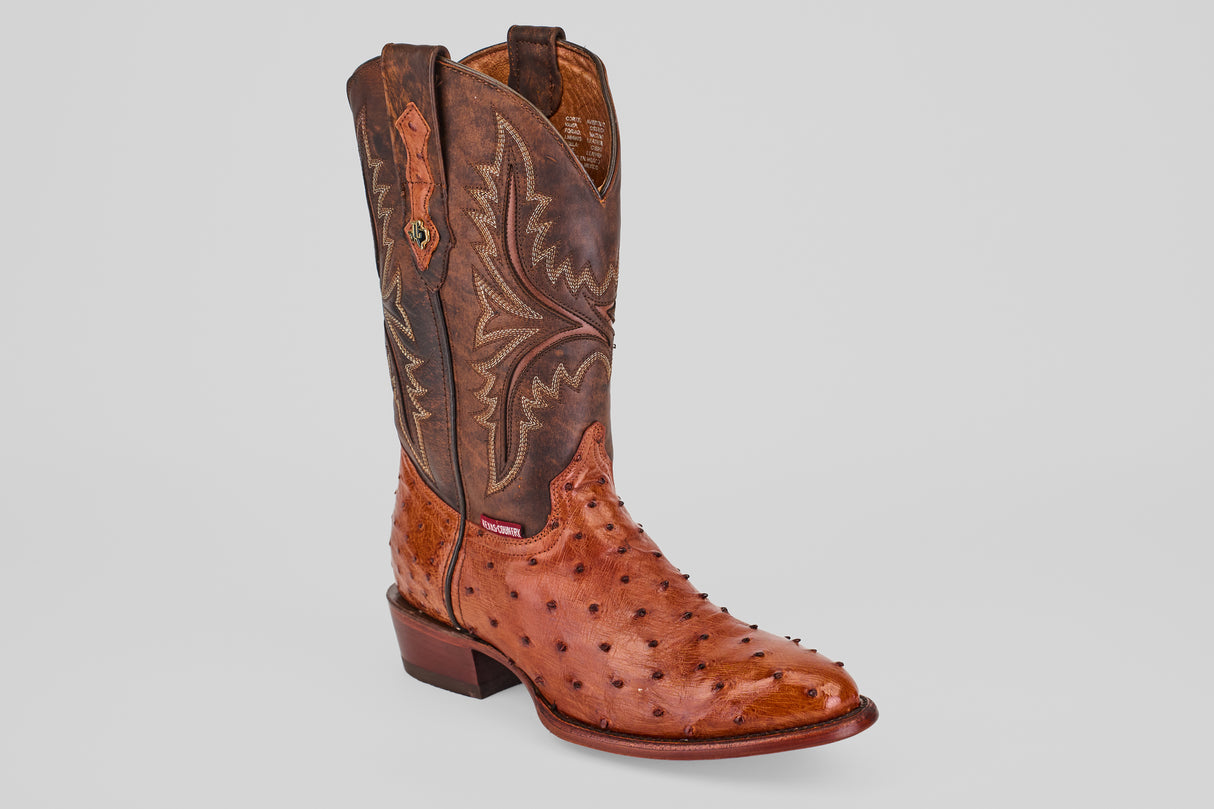 A single Exotic Full Quilt Ostrich - Brandy - Round Toe boot, featuring brown quilted ostrich leather with decorative shaft stitching and a bumpy foot texture, stands upright on a plain, light background.