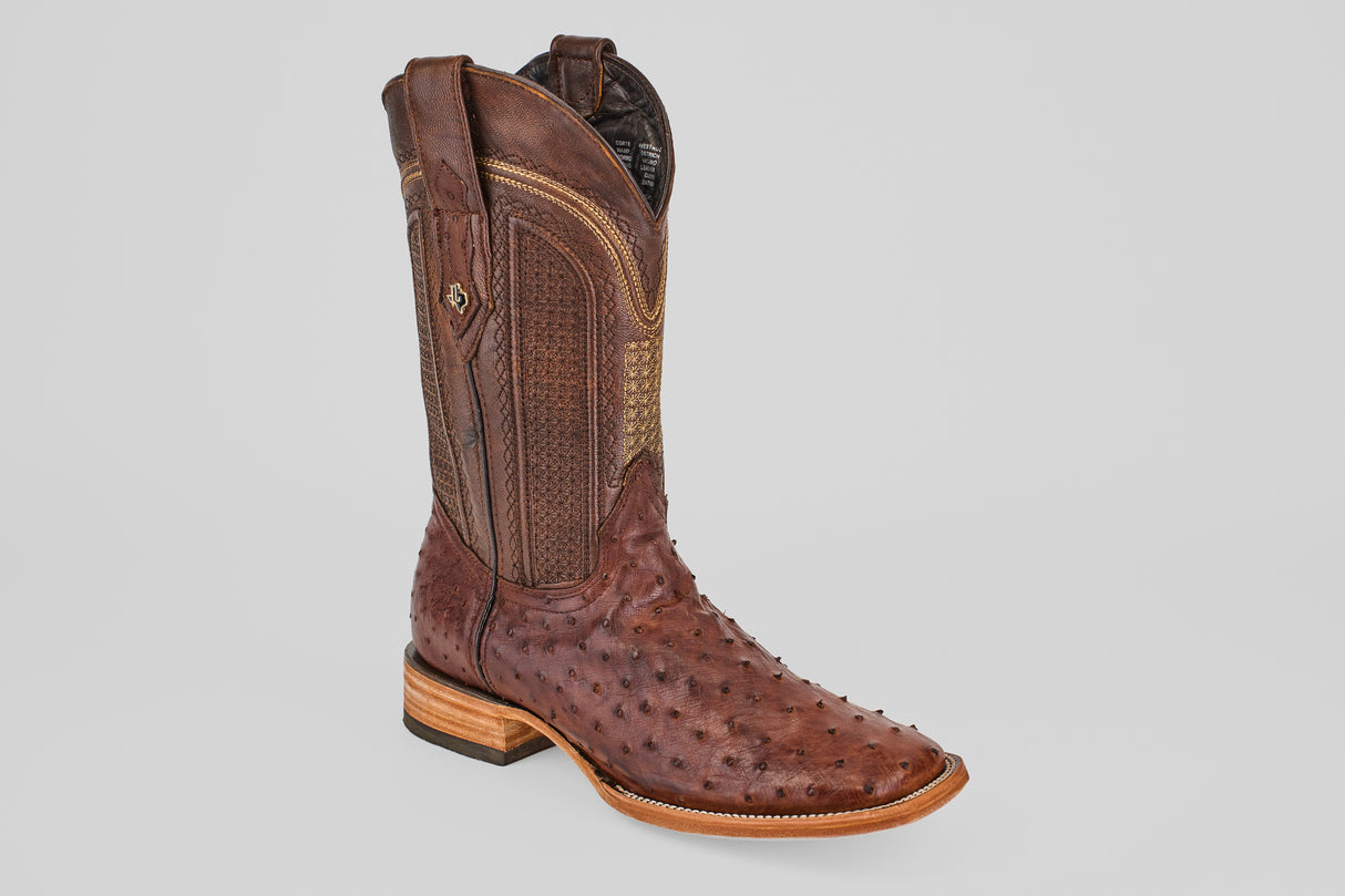 The Exotic Full Quilt Ostrich - Brown - Square Toe boot features decorative stitching, a bumpy ostrich leather texture, wooden heel, and square toe, set against a light gray background.
