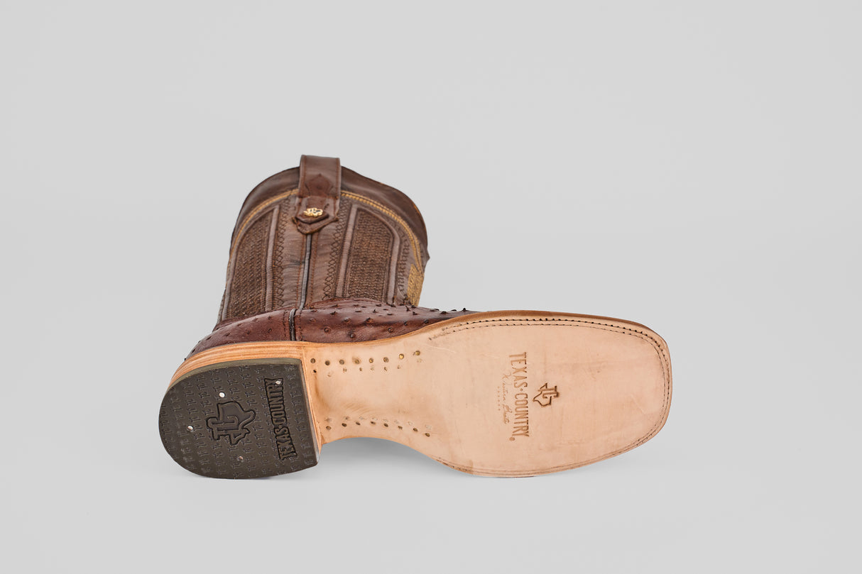 The Exotic Full Quilt Ostrich - Brown - Square Toe boot features a textured upper, smooth sole with TEXAS COUNTRY branding, a black textured heel, and classic cowboy style—ideal for square toe boot fans.