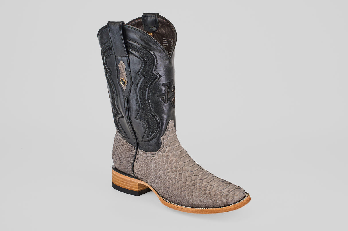 The Tanner - Matte Gray - Square Toe is a single cowboy boot with a light brown Python Gris Nobuck snakeskin-textured foot and a tall black leather shaft with decorative stitching, displayed on a plain light gray background.