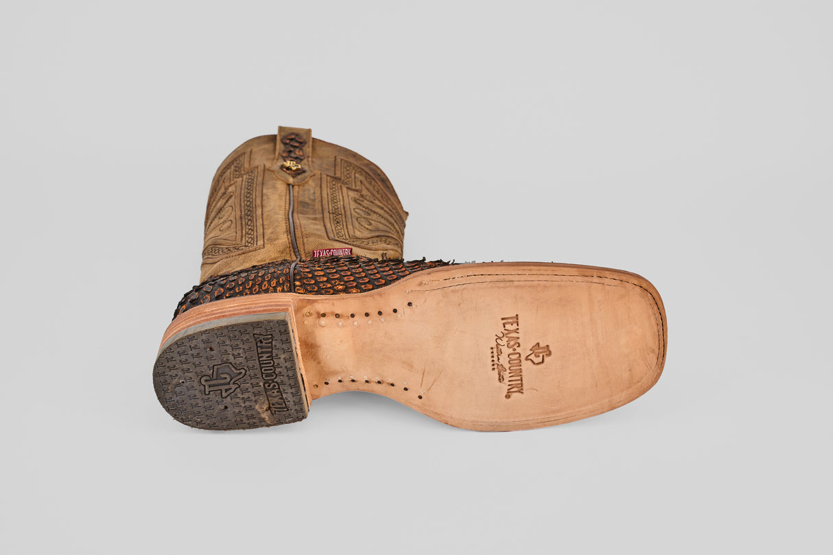 The Tanner Jumbo – Chestnut – Square Toe cowboy boot features detailed stitching, the Twisted X logo stamped on the sole, a textured heel, and showcases classic craftsmanship in its brown chestnut upper and square toe design.