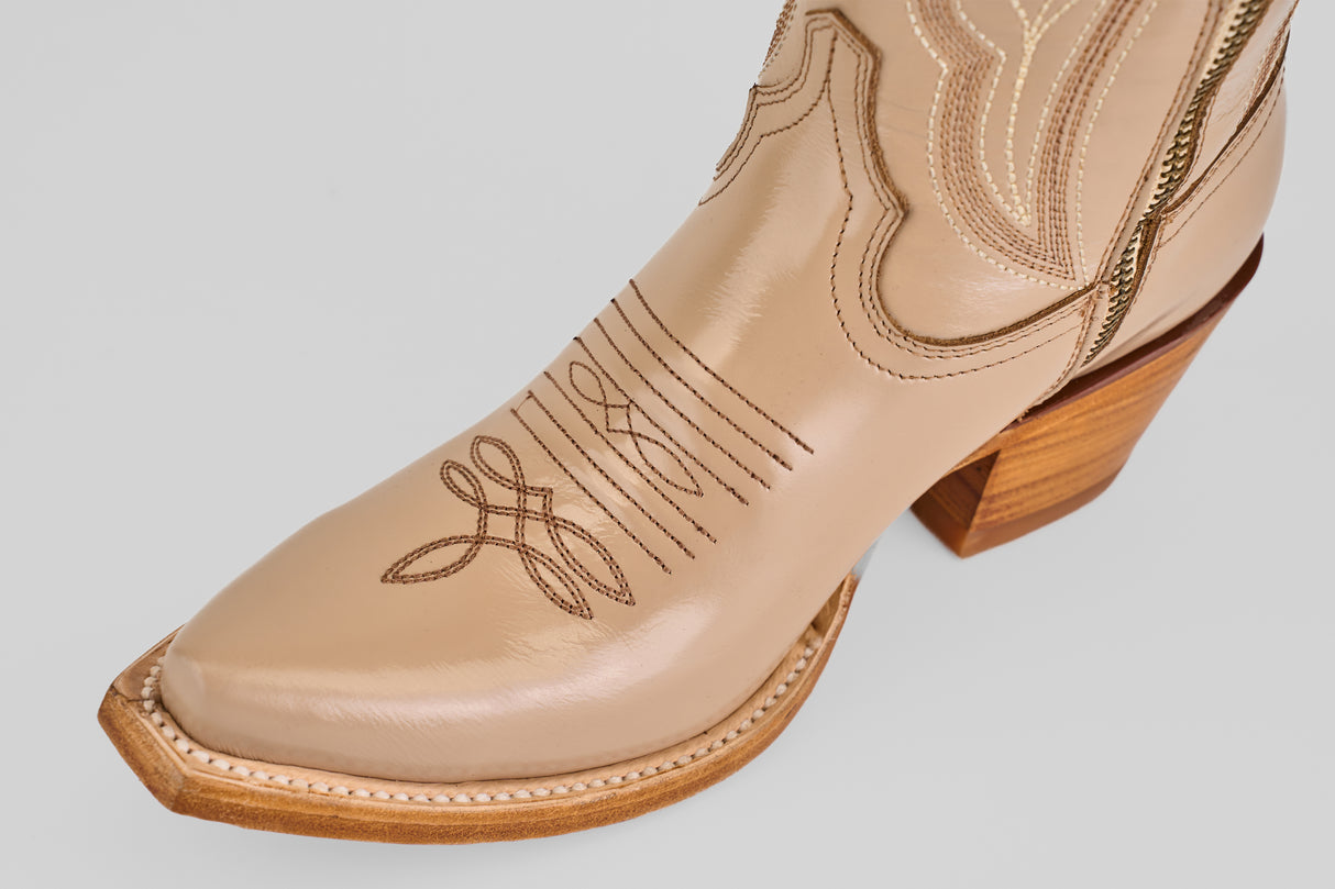 Close-up of the Allison Cream Tall Shaft Snip Toe boot in tan leather with decorative toe stitching and a wooden heel, shown against a light gray background—ideal for those seeking stylish women's cowboy boots.