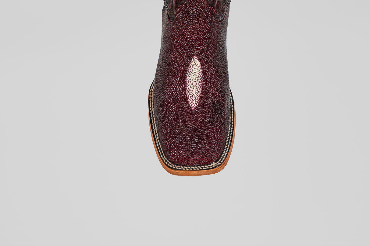 A close-up, top view of the Ranger – Wine – Square Toe boot shows textured, shiny maroon stingray leather and light brown welt stitching around the sole, set against a plain gray background.