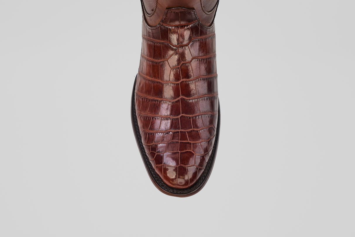 A close-up top view of the James Platimun - Dark Cogñac - Roper Toe (Diamond), featuring brown crocodile-patterned leather styled like men's western boots, set against a plain light background.