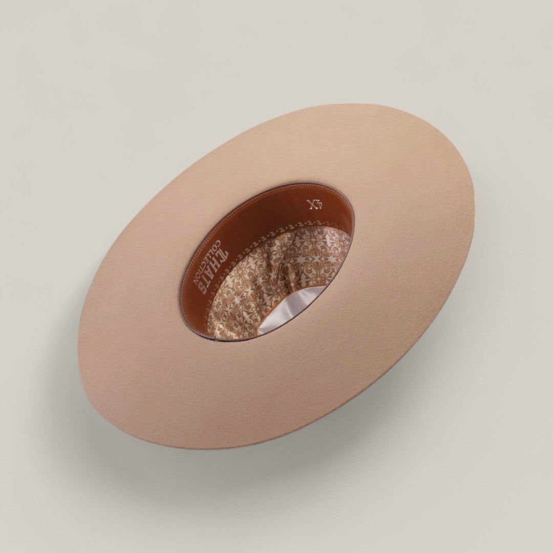 The 4x - Natural - TC Hats Open Crown Texana Western hat, in light beige, is displayed upside down to showcase its inner decorative lining and brown band, resting on a neutral surface.