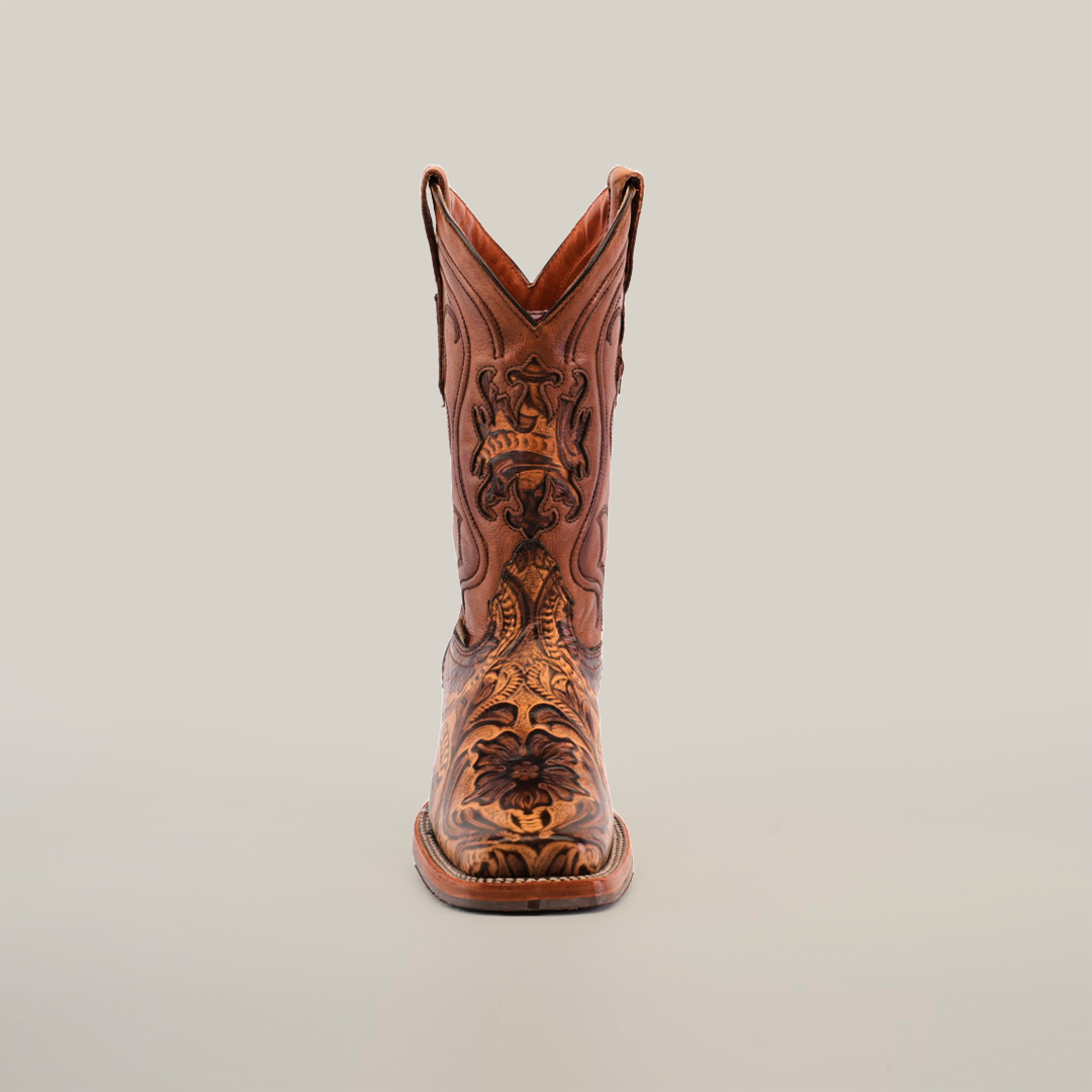 The Handtooled Leave Orix cowboy boot exhibits a front view of premium brown cowhide leather, adorned with floral and geometric embroidery on white. Its elegant design is complemented by handtooled details and a slip-resistant sole for enhanced stability.