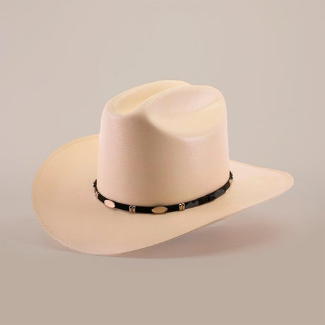Cream-colored cowboy hat with a wide brim and a dark band featuring light oval decorations, set against a plain light background.