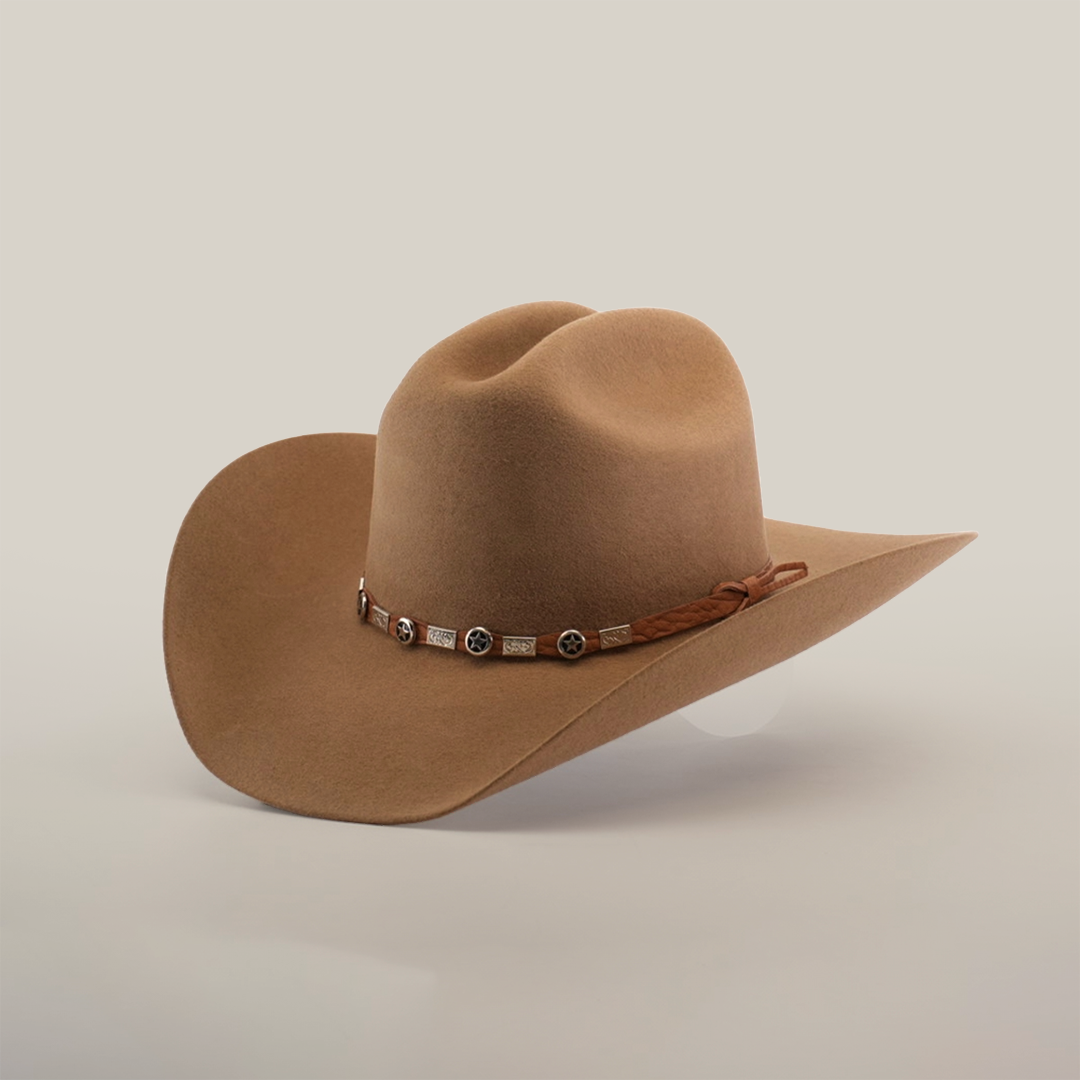 A brown cowboy hat with a wide brim and a decorative leather band adorned with metal accents, set against a plain, light background.