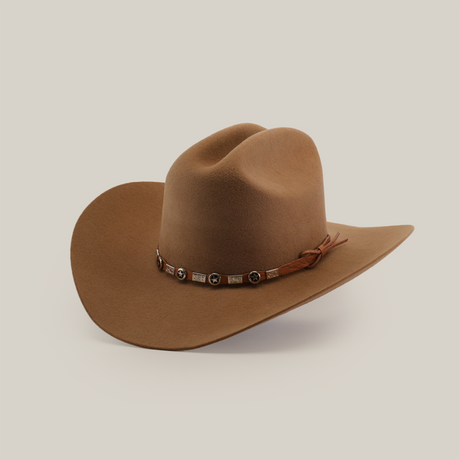 A brown cowboy hat with a wide brim and a decorative band featuring star-shaped studs and tassels, set against a light gray background.