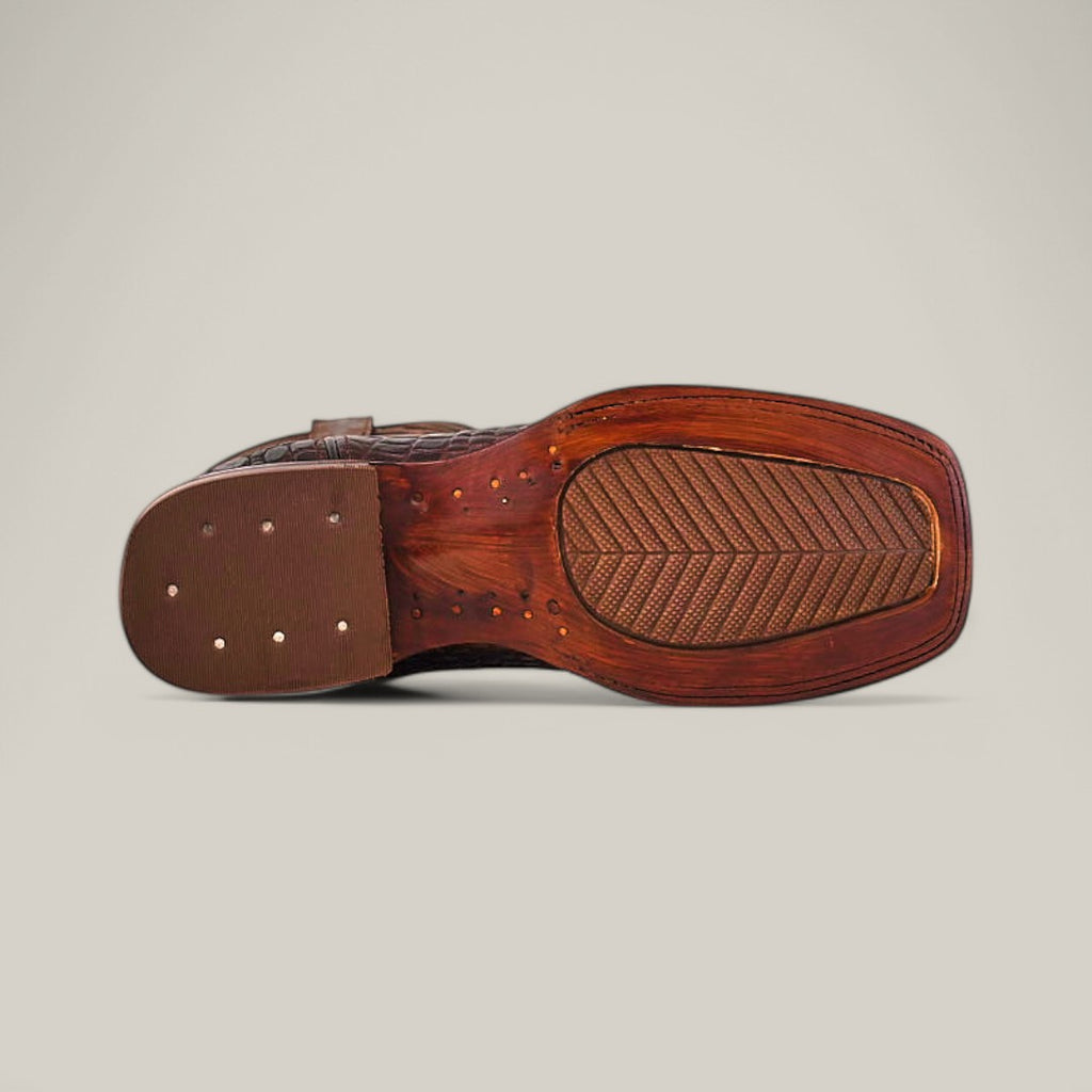 The image features the underside of the Alligatoar Horn Back Print Brown - Square Toe dress shoe, highlighting its wooden sole with a textured rubber heel and visible threads and studs. The shoe is elegantly captured against a plain off-white background.