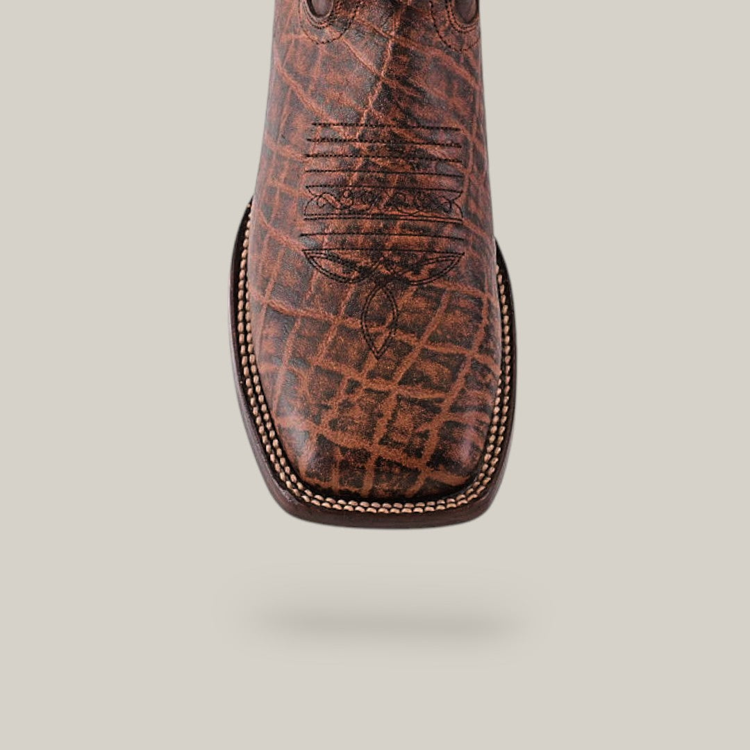 Close-up of the Mamut Grimm Brown - Square Toe cowboy boot featuring premium leather, a detailed stitched design on top, and a textured pattern with contrasting stitching along the edge against a neutral background.