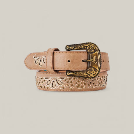The Sierra Fawn Belt - Texas Buckle features elegant floral carvings on tan leather with a decorative brass buckle, coiled attractively on a beige background, making it an essential women’s wardrobe accessory.