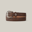 The Brown Plain Belt - Rustic Buckle is a sophisticated accessory, featuring a rustic buckle with intricate floral engravings. Its texture and edge stitching elegantly contrast against a plain beige background.