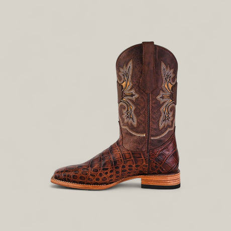 The Jonh - Brown - Square Toe boot features a crocodile-patterned lower section, decorative stitching on the shaft, and a stacked wooden heel, highlighting quality craftsmanship against a plain beige background.
