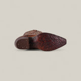 The Gina - Brown - Snip Toe boot is shown from the sole, displaying intricate floral patterns carved into brown leather and metal studs on the heel, set against a plain light background.