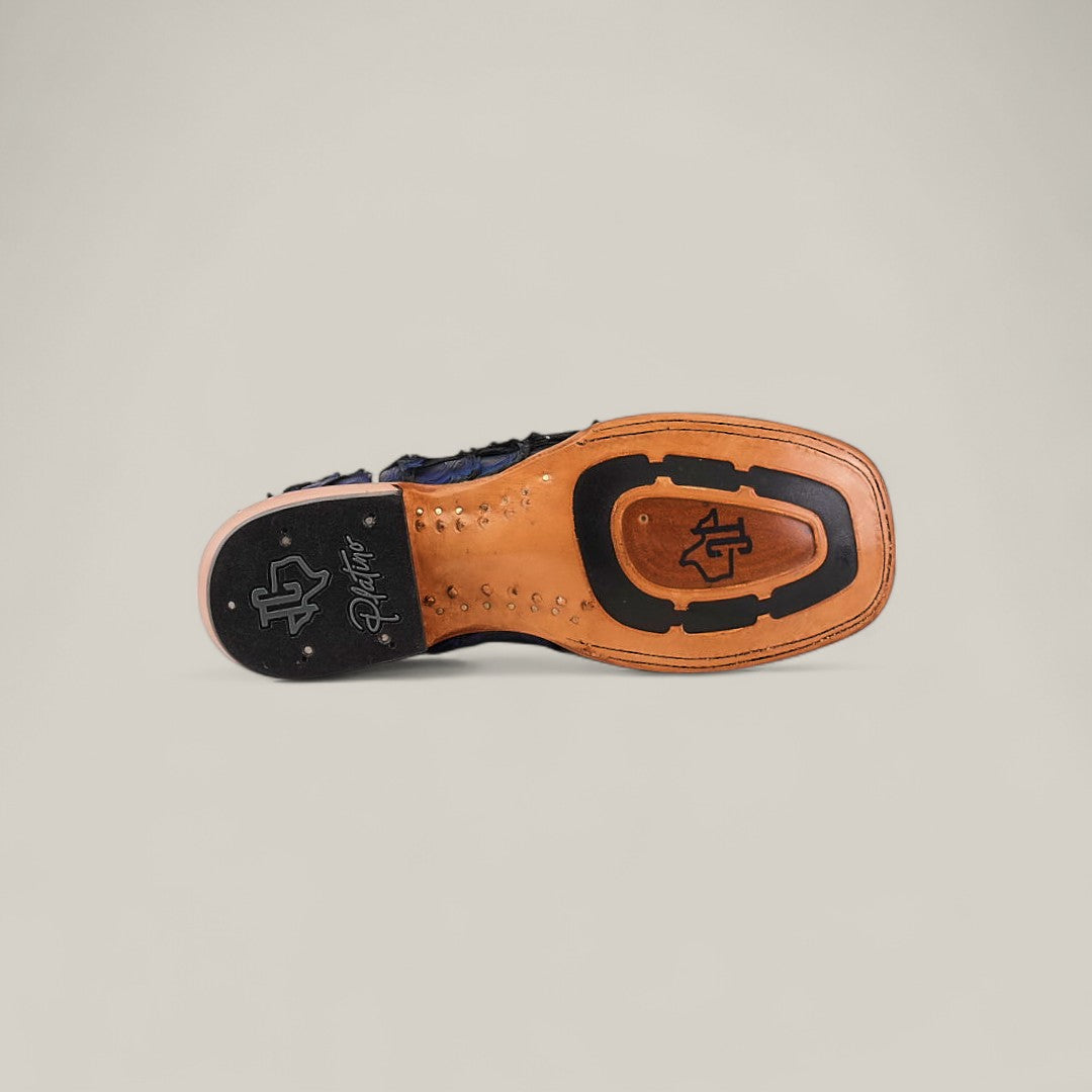 The image displays the sole of the Exotic Pirarucu Fish - Navy Black - Square Toe boot, featuring a tan leather base with black rubber grip details and signature logos near the heel and center, set against a plain light gray background.