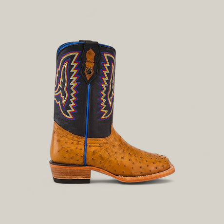 The Exotic Full Quilt Ostrich Fawn - Square Toe - Kids Boot displays Western style with a tan ostrich leather lower, stacked wooden heel, and black upper with colorful zigzag and stitched designs outlined in blue, red, and yellow. Profile view on neutral background.