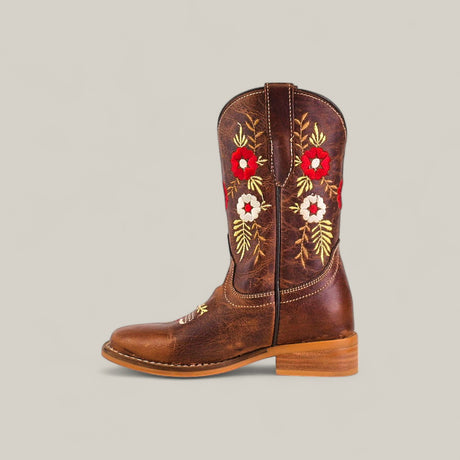 The Karo Brown - Square Toe - Kids Boots feature a classic design with a low wooden heel and brown leather shaft, adorned with red, white, and yellow floral embroidery on a plain beige background for comfort and style.