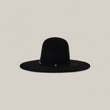 The 10X Grizzly - Tacchino is a wide-brimmed black felt hat with a rounded open crown and a small red accent on the band, shown against a simple beige background.