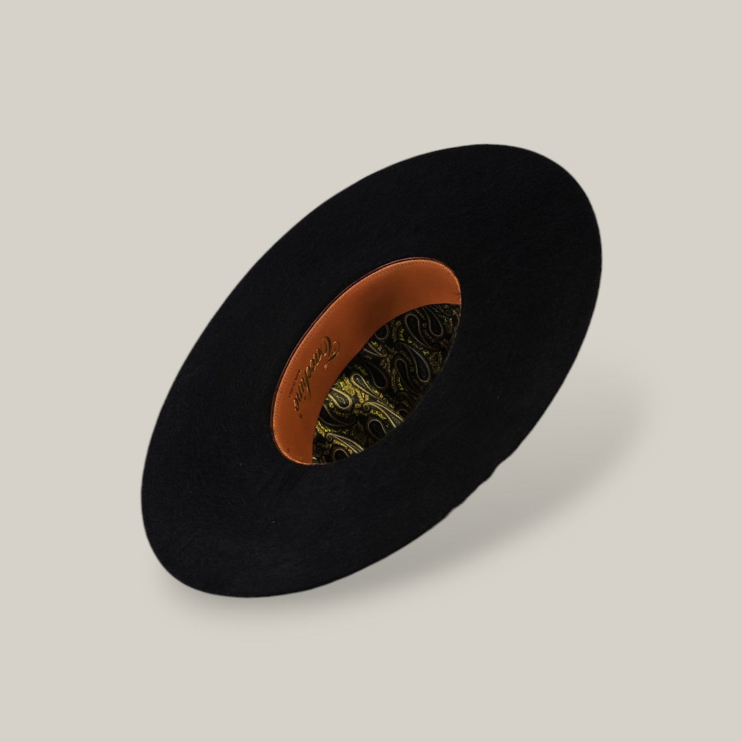 The 10X Grizzly - Tacchino is a black felt open crown hat, shown from above to display its tan leather inner band and green and gold paisley lining, set against a plain beige background.