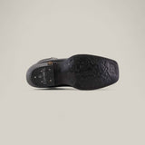 The image displays the sole of the Josie Full Black - Short Shaft - Narrow Square Toe, featuring intricate floral patterns and LUX SEMNLUX embossed near the heel, set against a plain light background for a chic, sophisticated look.