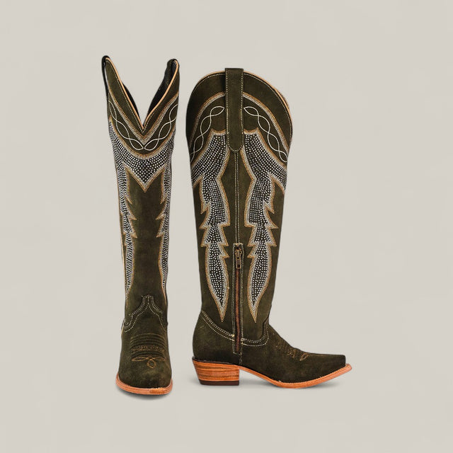 The Della Olive Green - Tall Shaft - Snip Toe boots feature decorative stitching, suede finish, pointed snip toes, and wooden heels. Displayed on a light gray background, one boot stands upright while the other leans slightly forward.