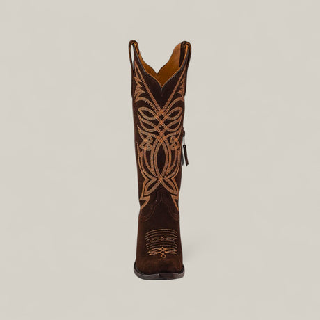 The Kellie Suede Brownie Leather Sole Tall Shaft Snip Toe boot is shown from the front, featuring dark brown suede and detailed light tan embroidery on a plain light background.