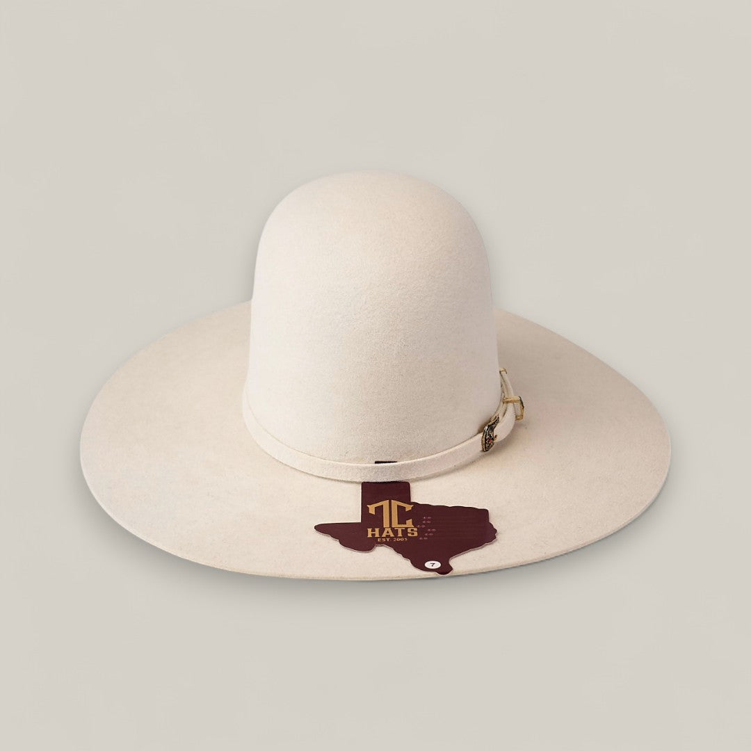 A wide-brimmed, light beige 10x White - TC Hats Western hat with a decorative band rests on a plain background. A Texas-shaped tag reads TC HATS in gold, emphasizing its classic Open Crown Texana style.