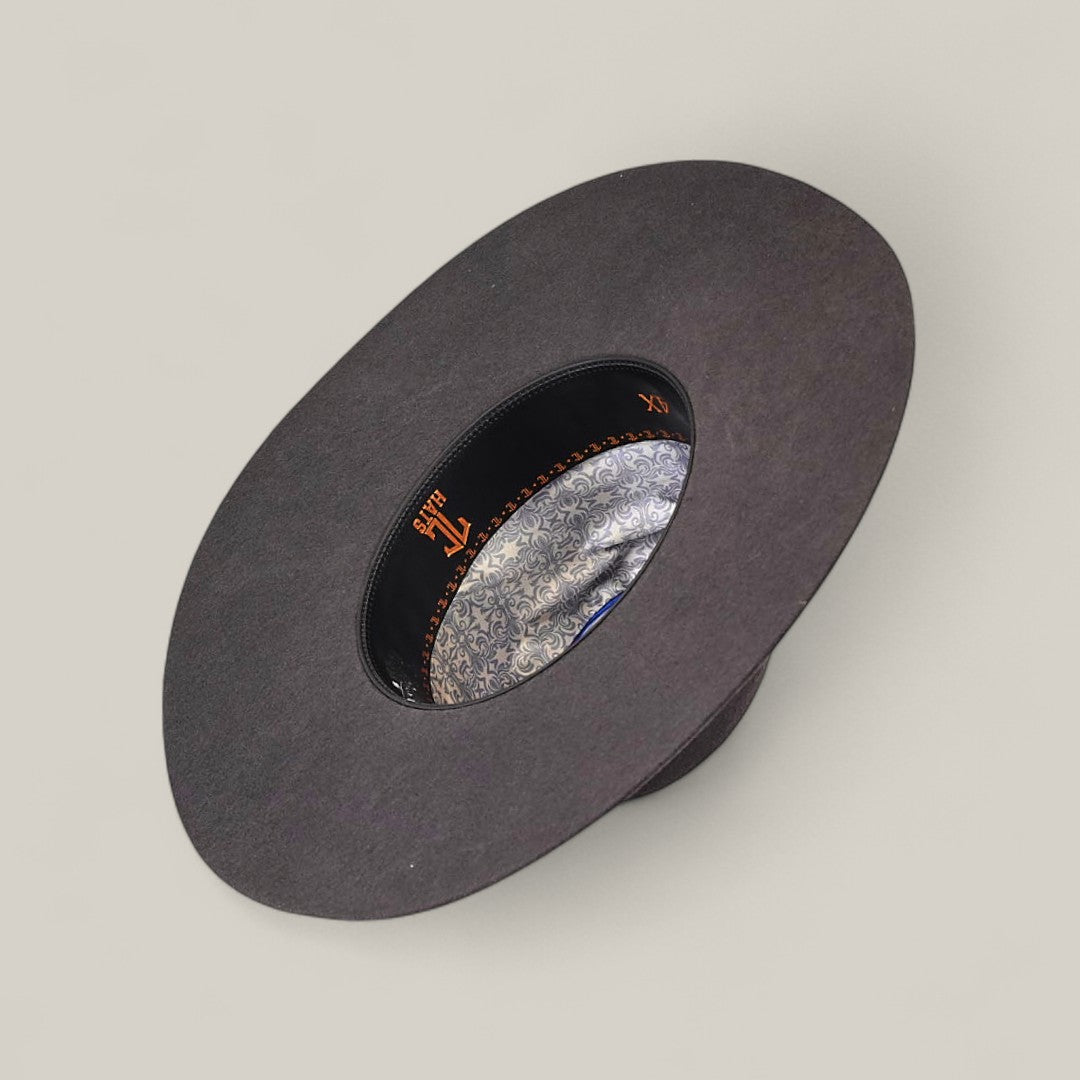 A 4X Gray - TC Hats wide-brimmed hat displayed upside down, showing a decorative silver-patterned inner lining and a black leather sweatband with orange stitching and gold lettering.