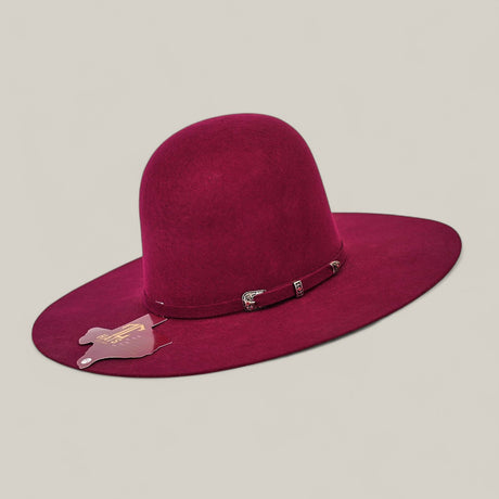 The 4X Burgundy - TC Hats is a wide-brimmed, deep burgundy Open Crown Texana Western hat featuring a thin decorative band and a small guitar-shaped tag on the brim, shown against a plain beige background.