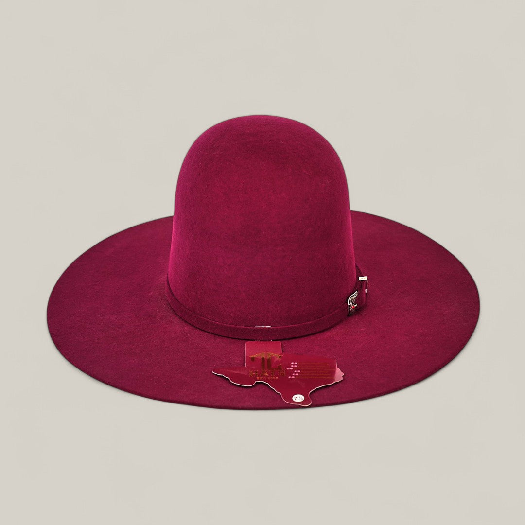 The 4X Burgundy - TC Hats features a wide brim, deep maroon color, domed crown, decorative band, and a Texas-shaped pin on the brim, set against a plain light gray background.