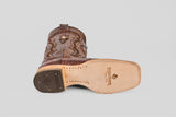 A brown Exotic Caiman Horn Back - Square Toe boot lies on its side, showing the tan sole with visible stitching, tread on the heel, and the Texas Country logo—an iconic style for fans of square toe boots.