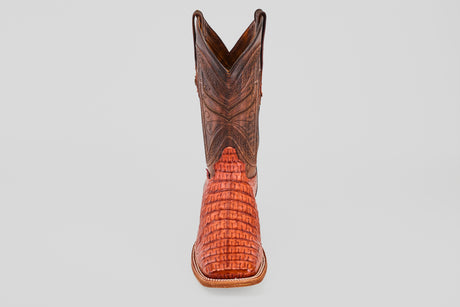 The Exotic Caiman Horn Back - Brandy - Square Toe boot, featuring a brown textured shaft and reddish patterned foot, is displayed facing forward on a plain light gray background.