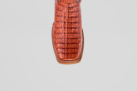Close-up of the toe of the Exotic Caiman Horn Back - Brandy - Square Toe boot, featuring a textured caiman pattern and detailed white stitching, set against a plain light gray background.