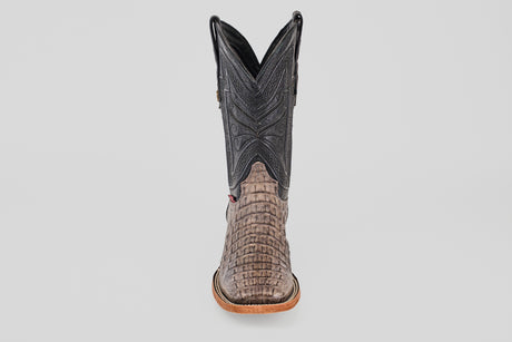 The Exotic Caiman Horn Back - Serpentine - Square Toe boot is shown from the front, displaying a textured reptile-like lower, dark stitched shaft, and light brown sole—a classic western look against a plain background.