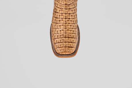 A close-up of the toe of the Exotic Caiman Horn Back - Antique - Square Toe boot, featuring a striking crocodile pattern in tan, set against a plain light gray background.