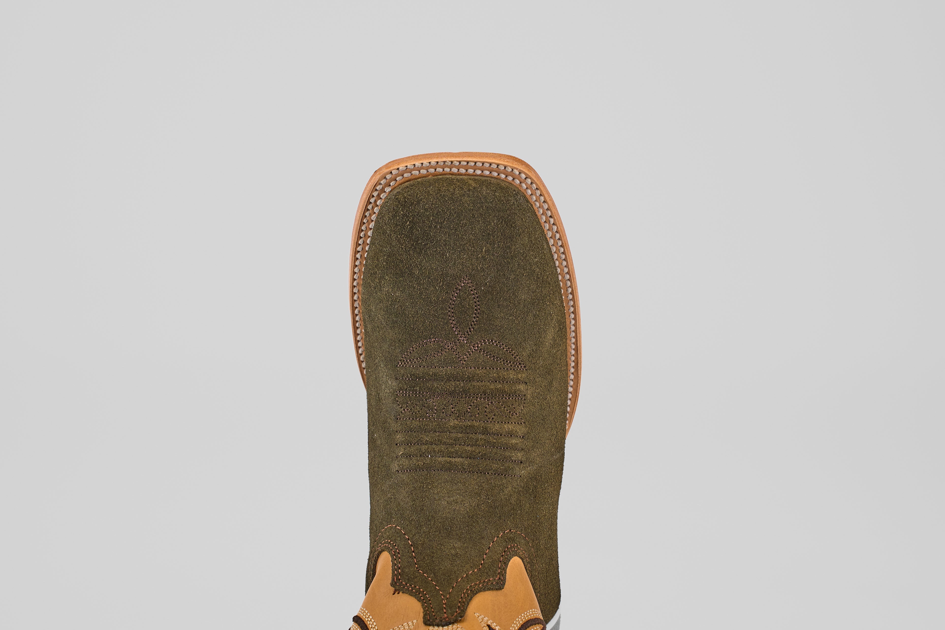 A close-up, top-down view of the Prime Suede Green Olive - Square Toe mens boot, featuring olive green suede with tan leather trim and decorative stitching, set against a plain white background.