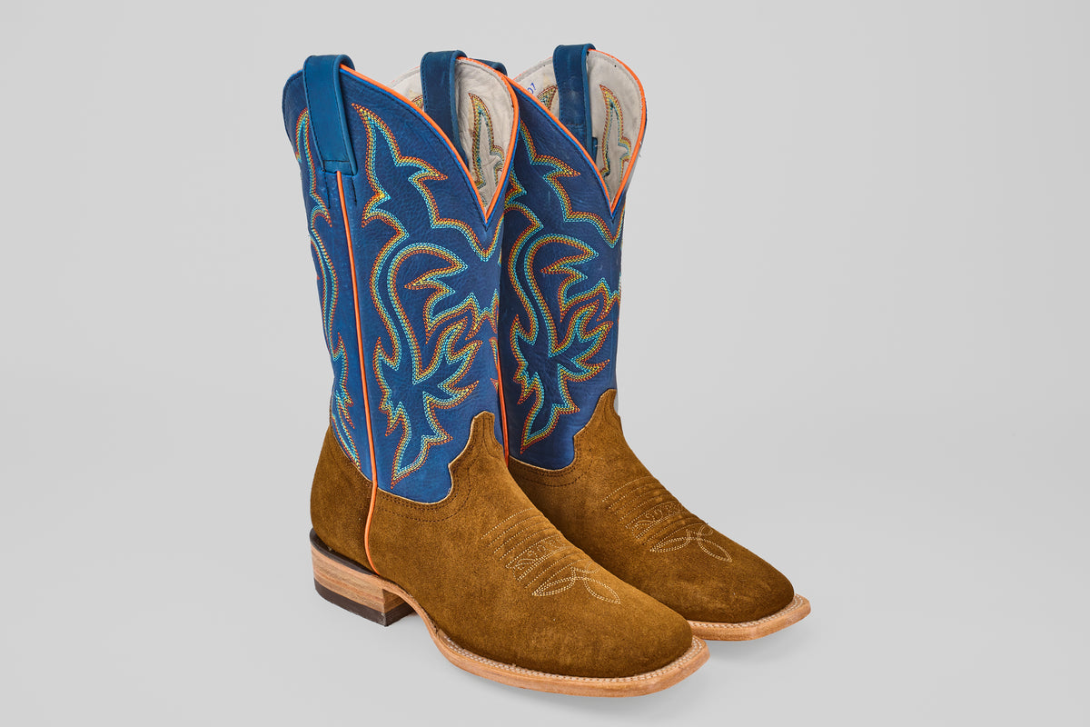 The Gold Suede - Square Toe boots feature brown suede foot and toe, blue leather shafts with colorful stitching, pull straps, and light tan soles, shown side by side on a plain light background.