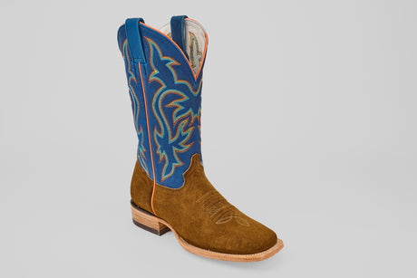 The Gold Suede - Square Toe cowboy boot features a brown suede foot, square toe, tall blue leather shaft with colorful stitching, pull straps, and a low wooden heel—an elegant addition to luxury footwear.