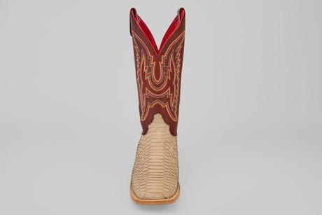 The Braxton - Cappucino - Square Toe is a mens boot with a light tan textured lower, tall dark brown upper with red, yellow, and white stitching, and a bold red lining. Shown on a plain gray background.