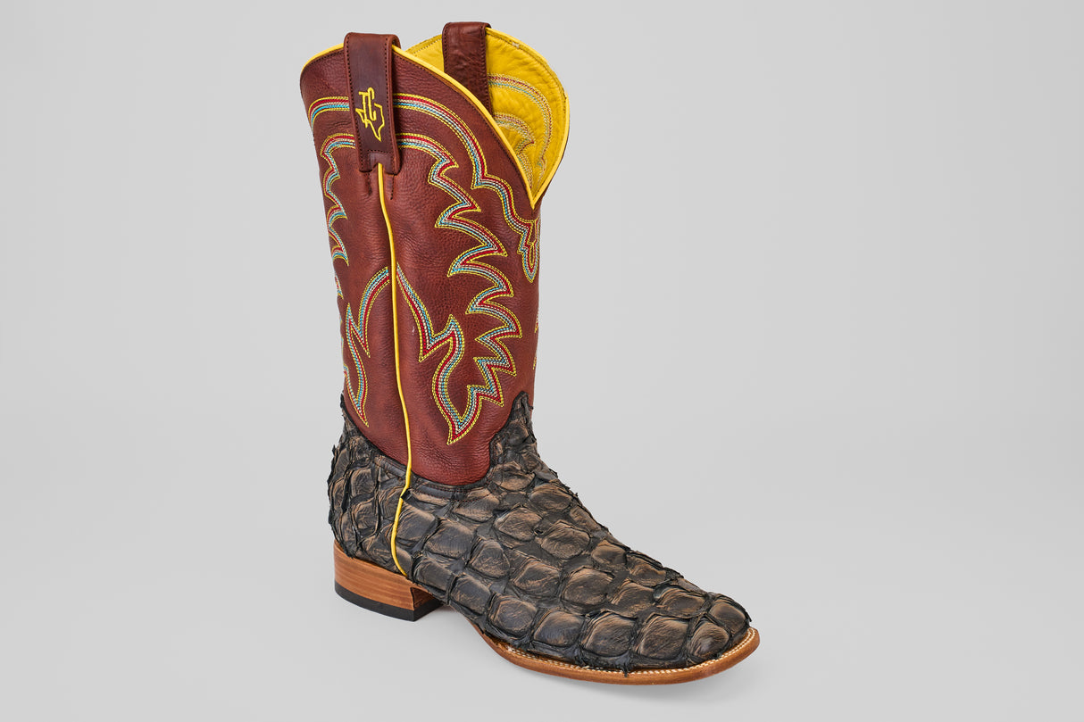 The Butch - Caramel - Square Toe boot features a brown leather shaft with yellow and white stitching and a textured dark brown pirarucu leather foot, giving it an exotic look similar to reptile skin.