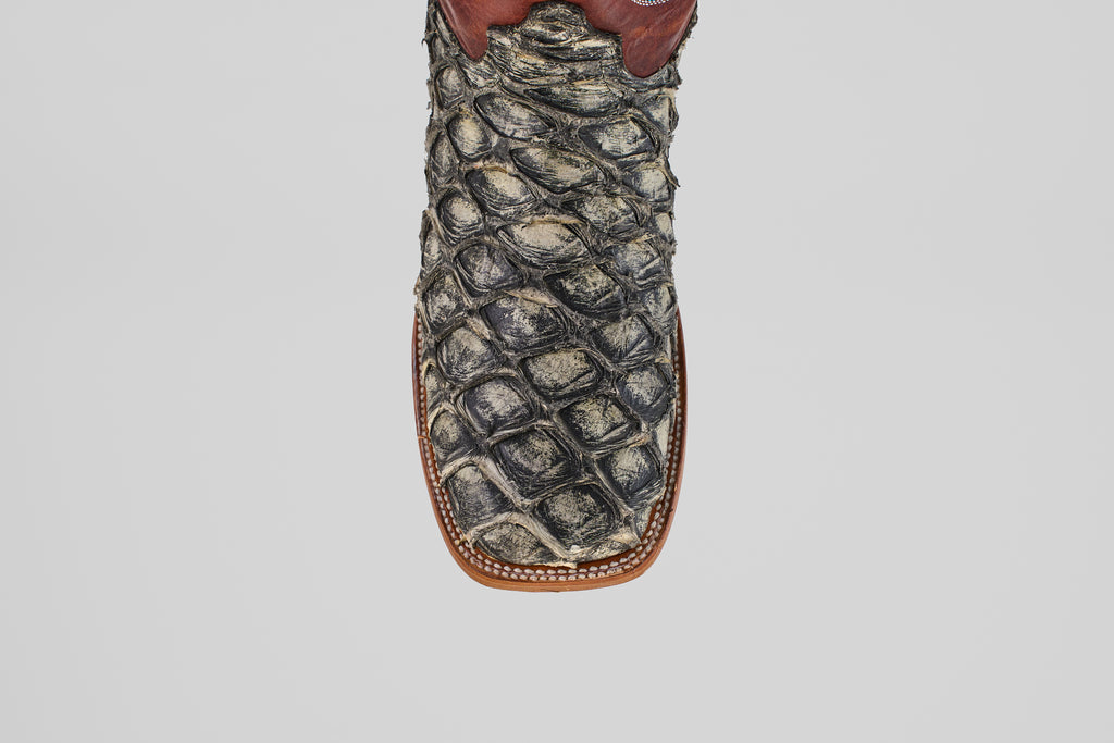 A detailed, top-down view of the Robinson - Newspaper - Square Toe boot highlights its textured Purarucu leather, brown trim, and white stitching—showcasing these distinctive handcrafted boots.