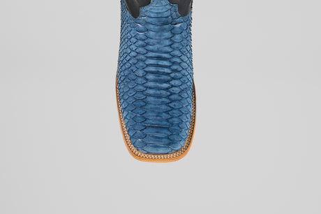 A close-up top view of the Kingsley - Blue Jeans - Square Toe boots reveals blue snakeskin, a square toe, and decorative stitching on a light brown leather sole—men’s boots built for standout style.