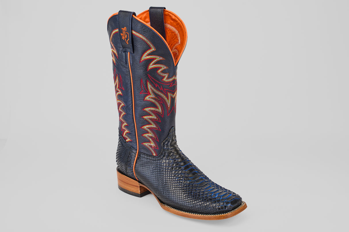 A single McGraw - Navy - Square Toe Boot with a textured black reptile-patterned lower, navy upper with orange, yellow, and red stitching, wooden heel, orange lining, from the Diamond Collection.