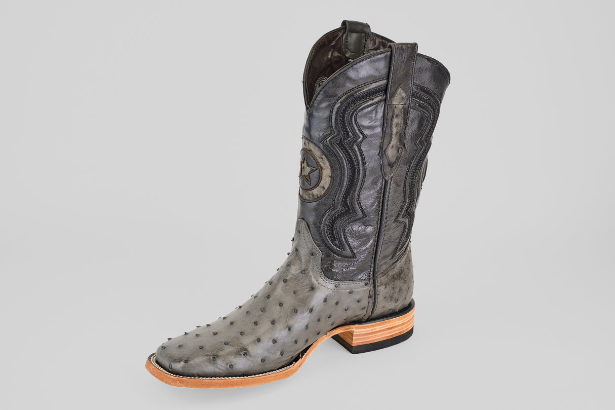 The Exotic Full Quilt Ostrich - Gray - Square Toe boot features decorative stitching, star detail on the shaft, textured ostrich leather, a wooden heel, and is displayed solo against a plain light gray background.