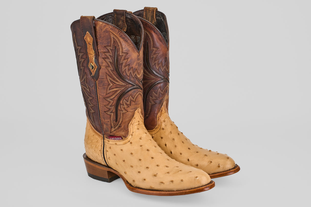 The Exotic Full Quilt Ostrich - Orix - Round Toe showcases light tan quilted ostrich leather on the foot and dark brown, intricately stitched shafts, all set against a plain light gray background.